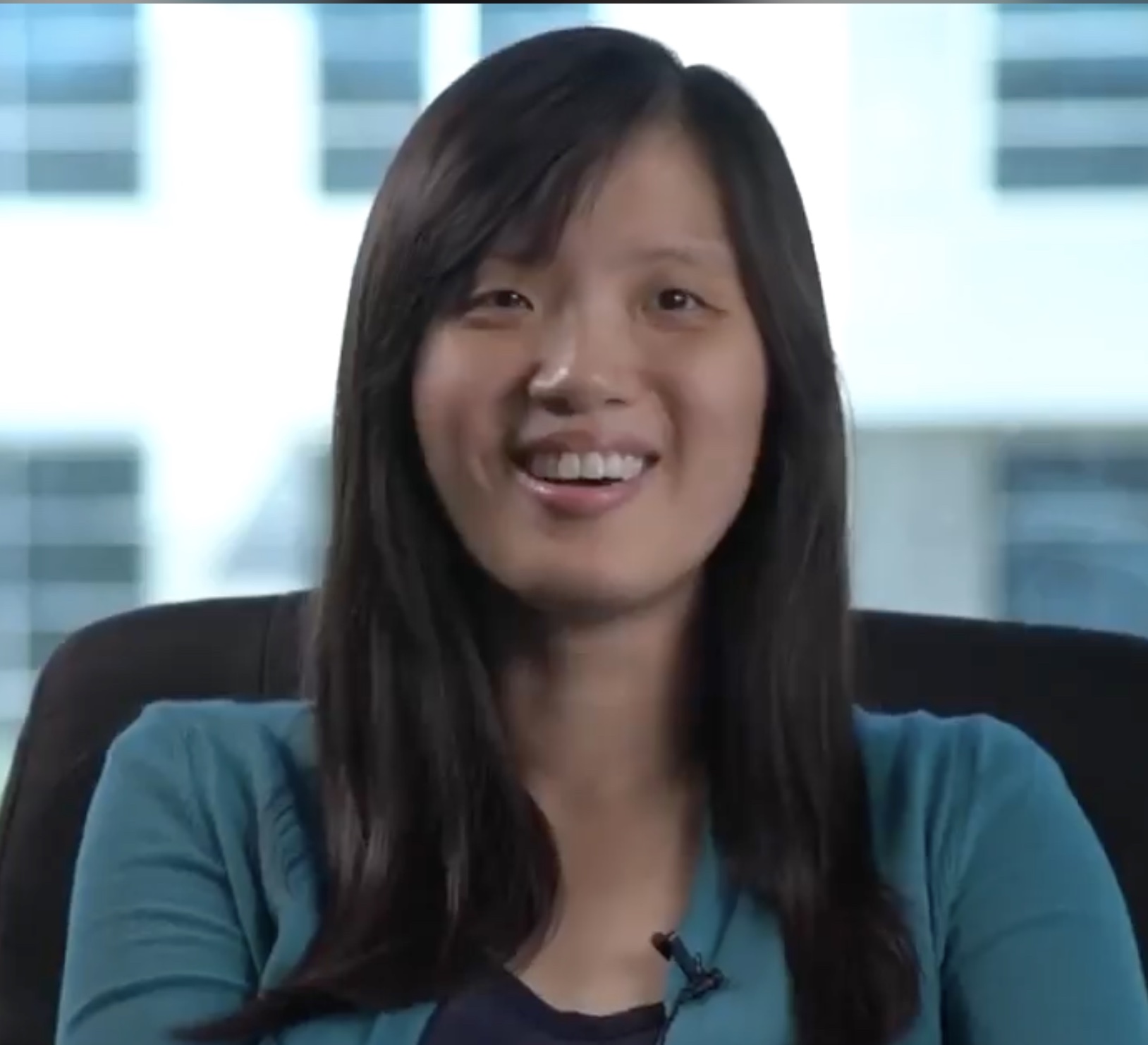 Cindy Lin with TRINITY International sitting in chair with stylish modern office windows in the background