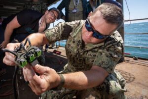 U.S. Navy maintainer dressed in fatigues tests electrical components aboard a Navy test ship